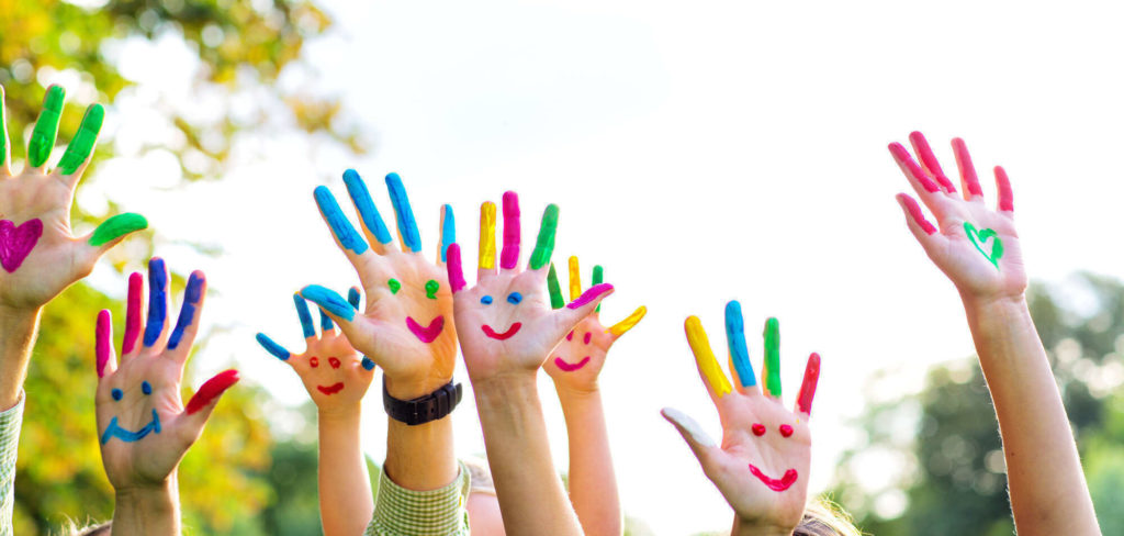 Des mains d'enfants coloriées et levées, connotant la prise en charge d'enfants par votre chauffeur de taxi.