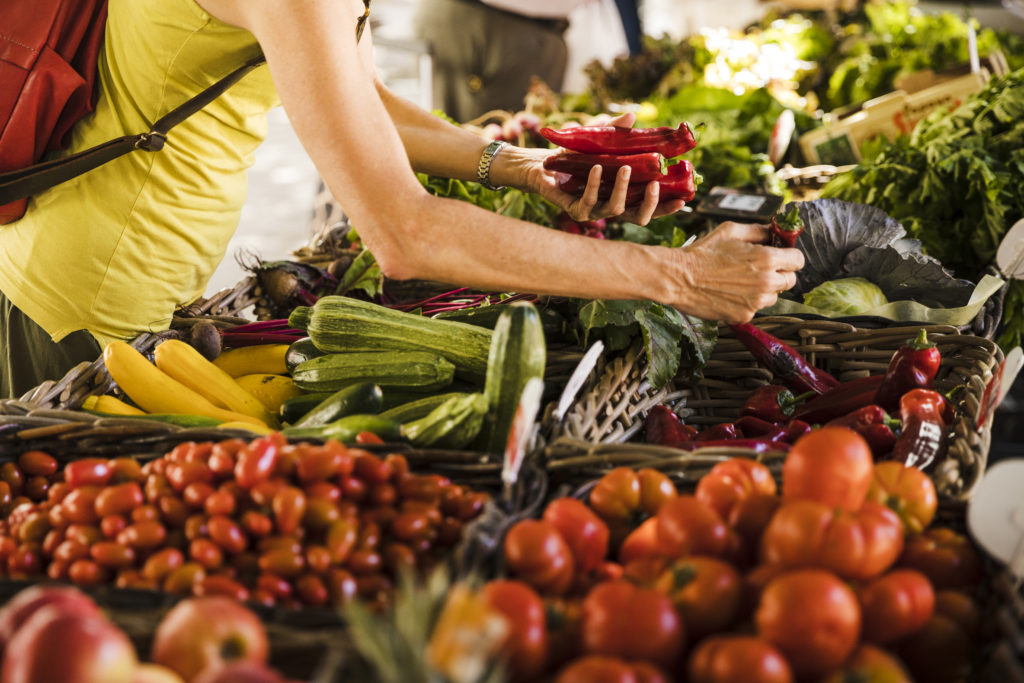 Une personne en train de choisir ses fruits et légumes, sur l'étal d'un marché en Sud-Gironde.